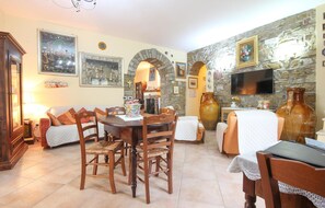 Cozy living room with a round dining table, comfortable sofa, and large stone wall featuring a mounted television.