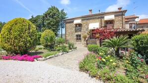 A stone building with a tiled roof, a gravel driveway, and a variety of flowering plants and trees. - 6 bedroom beautiful home in Perdifumo (Perdifumo)