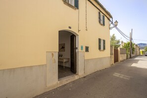 Una calle estrecha con un edificio que tiene una entrada pequeña y un letrero que indica un baño.