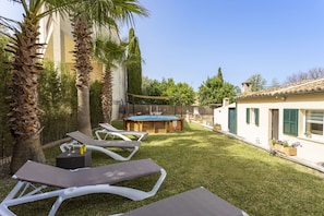Patio trasero con sillones de descanso, mesa de billar y jacuzzi.