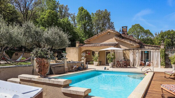 Una piscina con hidromasaje, mobiliario exterior y un patio cubierto.