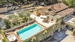 Un área de piscina en la azotea con un jacuzzi, sillones de descanso y una pérgola.