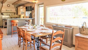 Una cocina con comedor, con muebles de madera, un ventanal grande y un reloj en la pared.