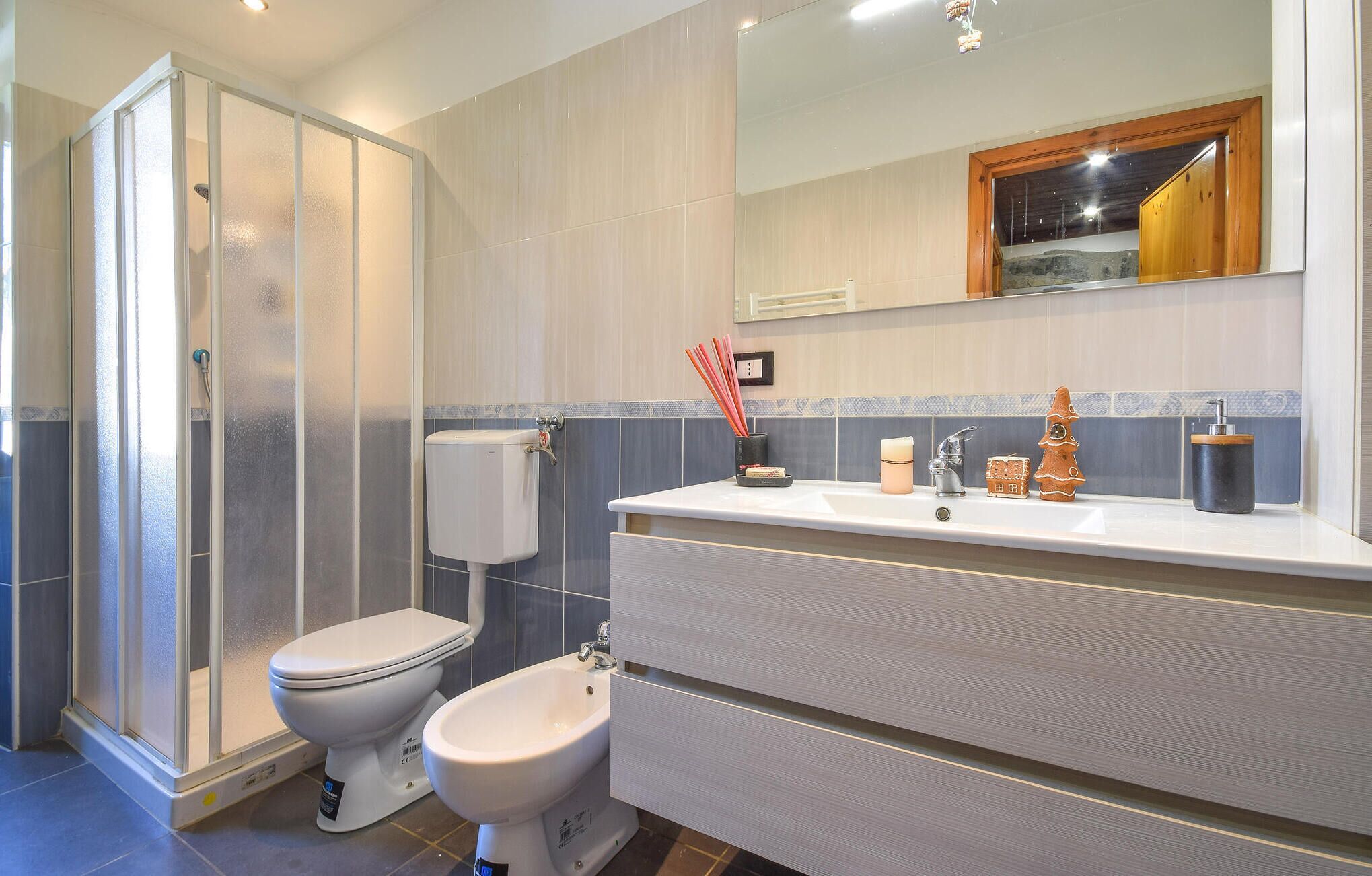 Uma casa de banho moderna com cabine de duche, sanita e lavatório com espelho em cima.