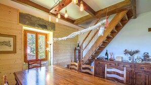 Un coin repas en bois avec une grande table et des chaises, un escalier avec des rampes en bois et un mur en pierre.