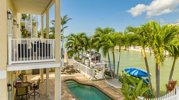 A pool area with a hot tub, outdoor furniture, and a view of the water.