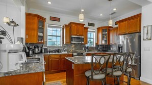 A modern kitchen with wooden cabinets, stainless steel appliances, and a central island with bar stools.