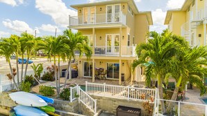 A two-story building with a balcony, a pool, and several kayaks.