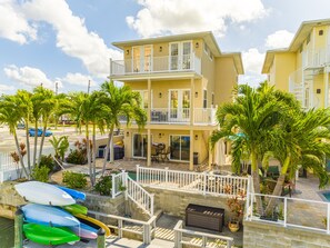 A two-story building with a balcony, a pool, and several kayaks.