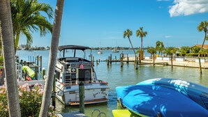 A marina with boats docked, palm trees, and a clear blue sky.