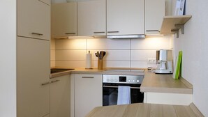 Een moderne keuken met een inbouwoven, een koffiezetapparaat en een messenblok op het aanrecht.
