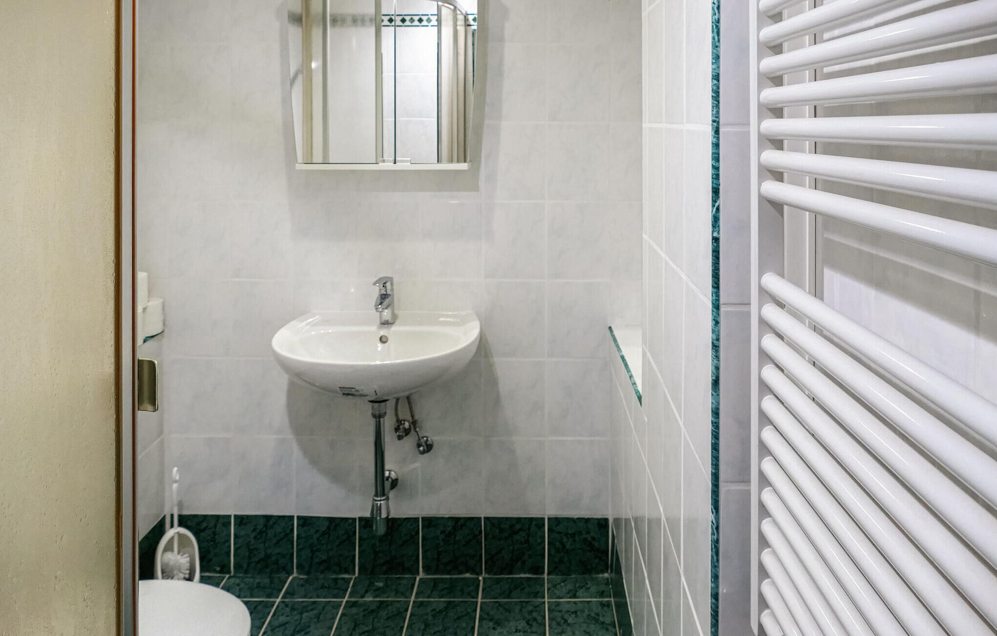 Een badkamer met een wit wastafel, een spiegel erboven en een toilet.