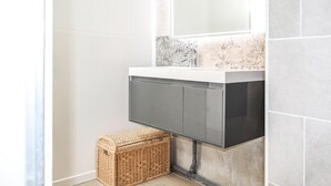 A bathroom with a white sink, dark cabinets, and a marble backsplash. - Beautiful apartment in noirmoutier-en-l'île (Noirmoutier-en-l'Île)