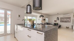 A modern kitchen with a large island, white cabinetry, and pendant lighting. - Awesome home in Donja Jagodnja (Donja Jagodnja)