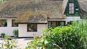 A traditional thatched-roof cottage with a green gable, potted plants, and a paved entrance. - 2 bedroom gorgeous home in Zierow OT Eggerstorf (Zierow OT Eggerstorf)