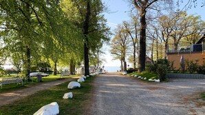 A gravel path leading to a beach, flanked by trees and rocks, with a bench and a building in the background. - 2 bedroom gorgeous home in Zierow OT Eggerstorf (Zierow OT Eggerstorf)