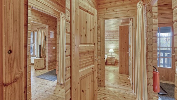 L’intérieur d’un chalet en bois comprend un couloir menant à une chambre, une petite salle de bain et une fenêtre offrant une vue agréable.