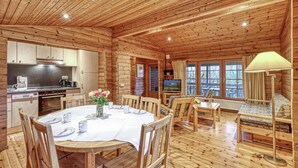 L’intérieur d’un chalet en bois comprend un coin repas, une cuisine et un téléviseur.