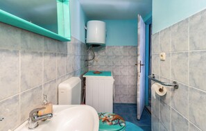Un baño con lavamanos blanco, inodoro, ducha y barra para toallas.