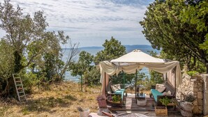 Ein gemütlicher Außenbereich mit Markise, Holzterrasse und Meerblick.