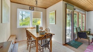 A dining area with a wooden table and chairs, a window with a view of trees, and a sliding glass door leading to an outdoor area. - Awesome home in Fårevejle with kitchen (Fårevejle)