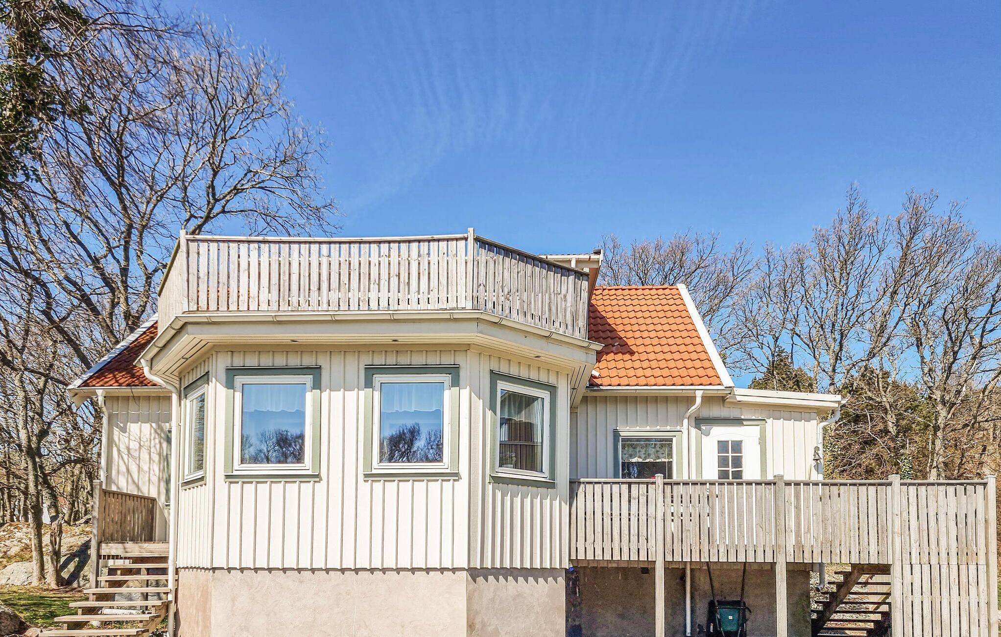 A two-story house with a balcony, a covered porch, and a red-tiled roof.