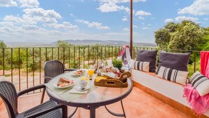 Eine Terrasse mit gedecktem Tisch für das Frühstück mit Blick auf eine schöne Landschaft.