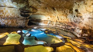 En grotta med naturliga klippformationer och en vattenyta som reflekterar ljuset.