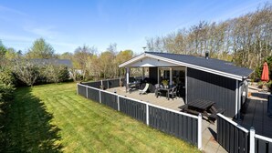 Une petite maison de plain-pied dotée d’un patio couvert.