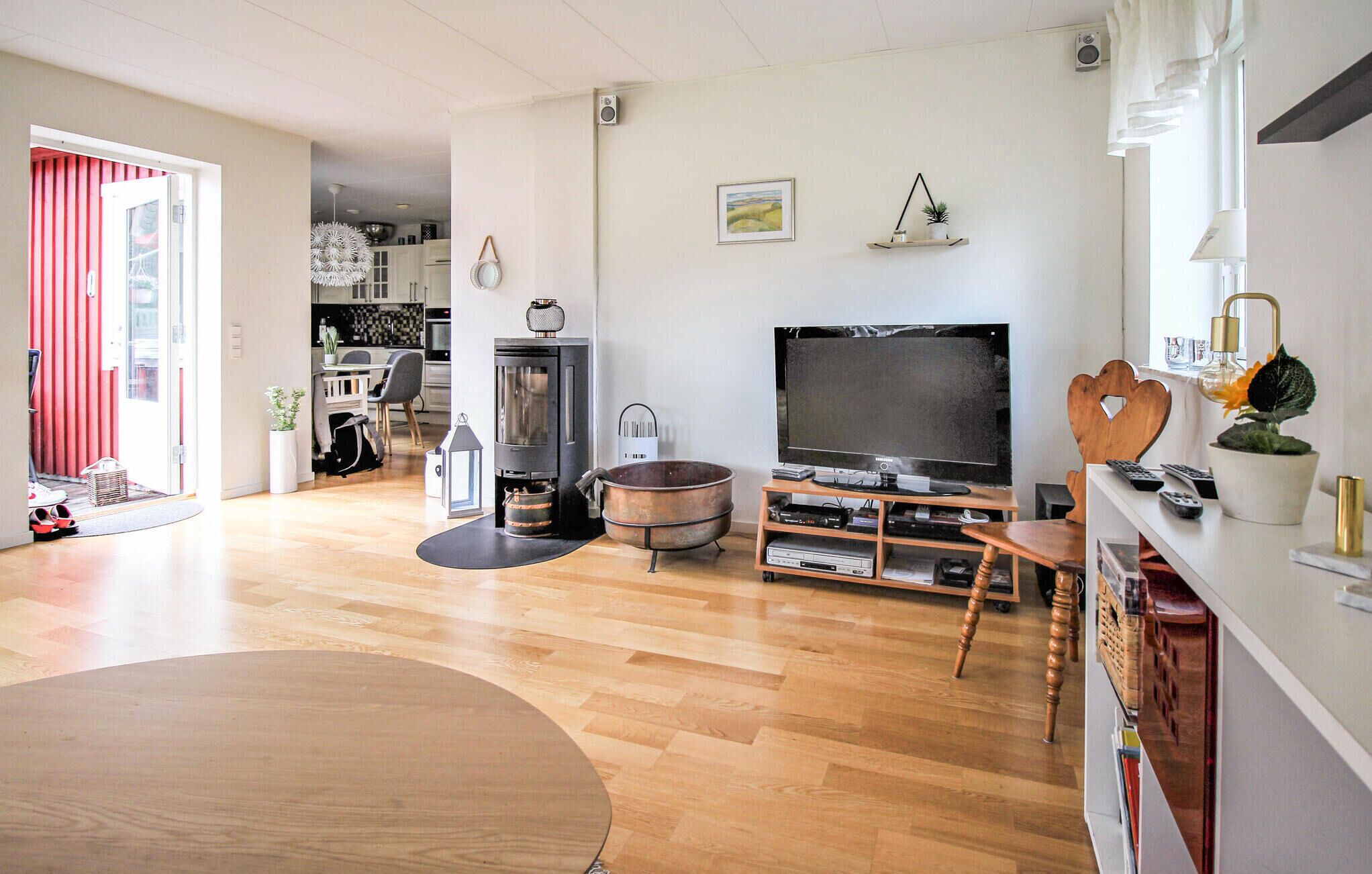 A living room with a wooden floor, a TV, a fireplace, and a dining area with a table and chairs.