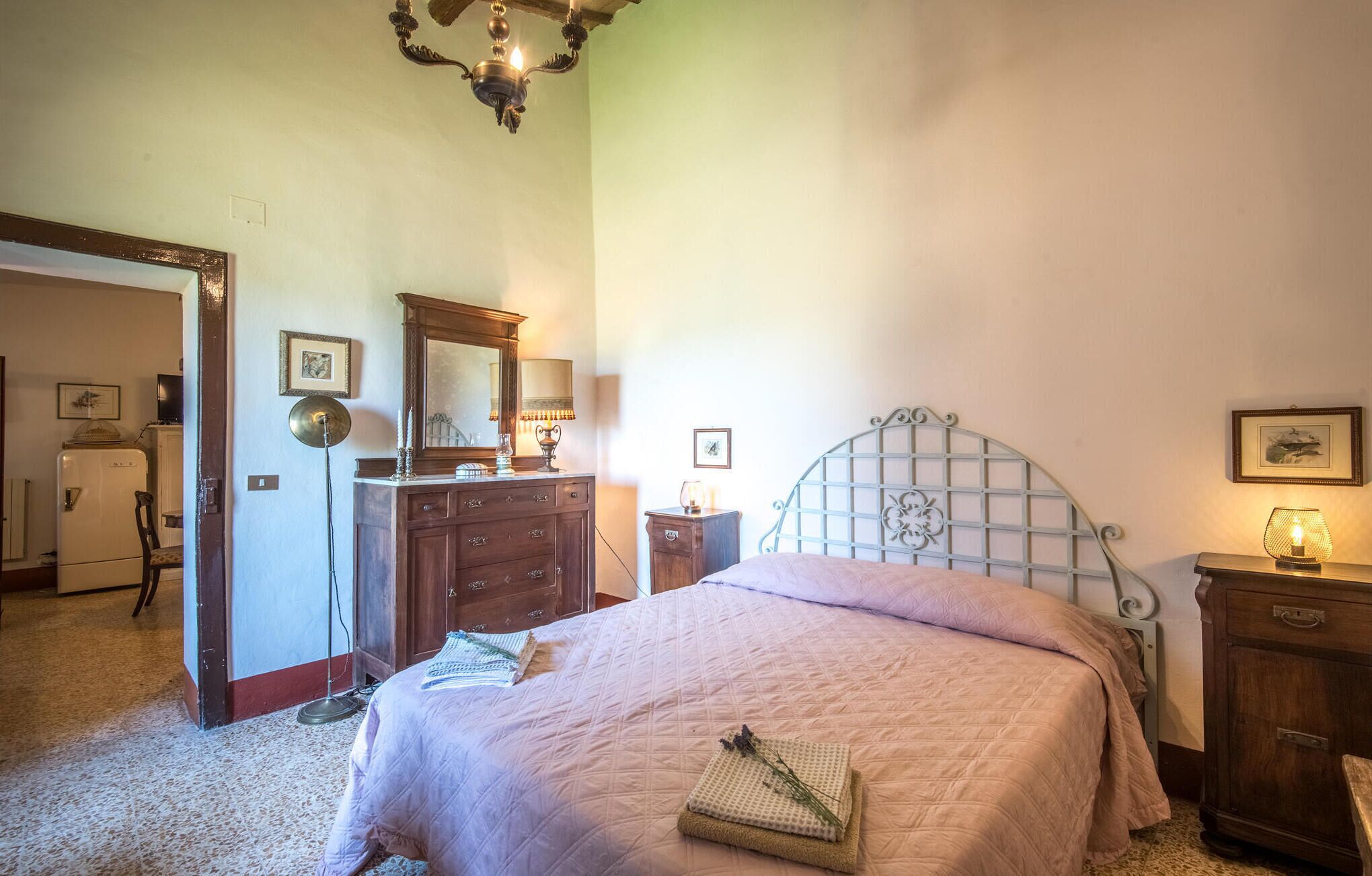 Une chambre à coucher avec un lit, une commode, un miroir et un lustre.