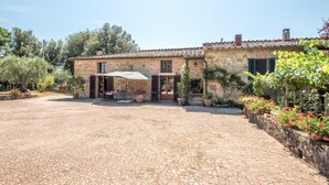 Un bâtiment en pierre avec une cour, une table entourée de chaises et des plantes en pot.