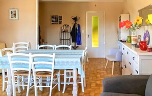 Un comedor con una mesa, sillas, un perchero y una puerta con una franja amarilla.