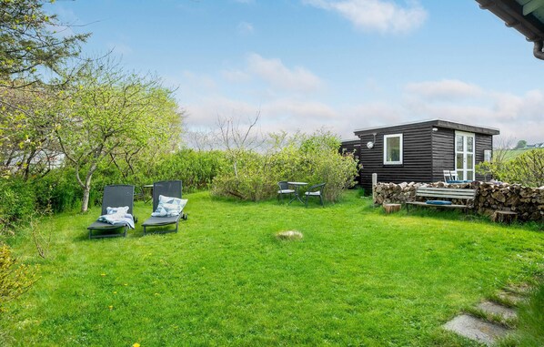 A small cabin with a grassy yard, two lounge chairs, and a table. - Cozy home in Skanderborg with kitchen (Skanderborg)