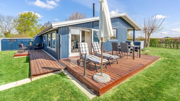 Ein modernes Haus mit einer Terrasse, Sitzgelegenheiten im Freien und einem großen Sonnenschirm.