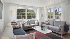 Ein modernes Wohnzimmer mit einer Couch, einem Couchtisch und einem Fenster mit Blick auf Grünflächen.