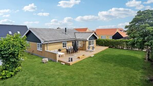 Ein Wohnhaus mit eingezäuntem Garten, einer Terrasse mit Gartenmöbeln und einem gepflegten Rasen.