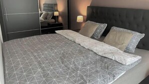 Ein Schlafzimmer mit einem großen Bett, einem dunklen Kopfteil und einem Kleiderschrank mit Spiegelüren.