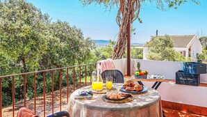 A balcony with a table set for breakfast, including croissants, fruit, and juice.