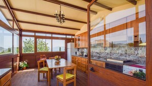 A spacious kitchen with wooden cabinets, a dining table with chairs, and large windows offering a view of the outdoors. - Beautiful home in Caccamo (Caccamo)