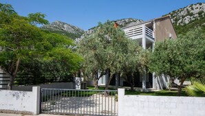 Ein Gebäude mit weißer Fassade, einem Balkon und einem Berg im Hintergrund.