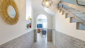 En modern inredning med en trappa, en hall som leder till ett matområde och en stor spegel på vänster sida.