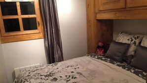 Ein Schlafzimmer mit einem Bett, Holzschränken, einem Fenster und einer Heizung.