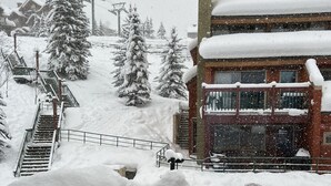 Un edificio cubierto de nieve con un telesilla al fondo.