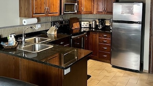 Una cocina moderna con armarios de madera, electrodomésticos de acero inoxidable y una encimera de granito negro.