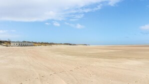 Een zandstrand met een gebouw op de achtergrond.