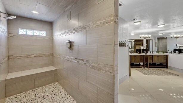 Ein modernes Badezimmer mit Dusche, Waschtisch und einem großen Spiegel.