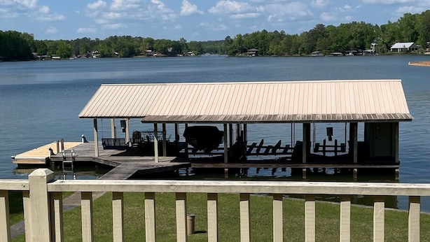A wooden deck with a covered seating area overlooking a lake.