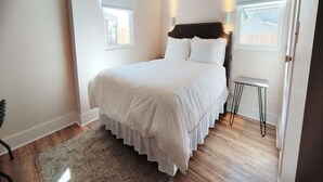 Ein Schlafzimmer mit einem großen Bett, einem kleinen Tisch und einem Fenster.