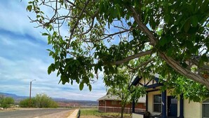 Einbungalow mit Garage, überdachter Veranda und Blick auf eine ländliche Gegend.